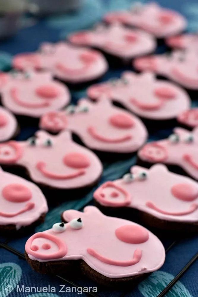A tray of decorated Peppa Pig Chocolate Cookies with pink royal icing and playful faces.