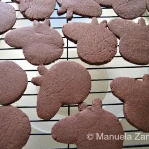 Freshly baked Peppa Pig shaped chocolate cookies cooling on a wire rack, undecorated.