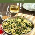 Finished bucatini with sardines and fennel in a pan, served with wine and toasted breadcrumbs.