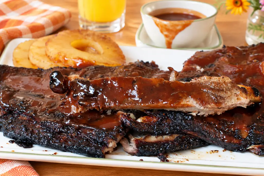 Glazed pork spare ribs served with pineapple rings and homemade barbecue sauce.