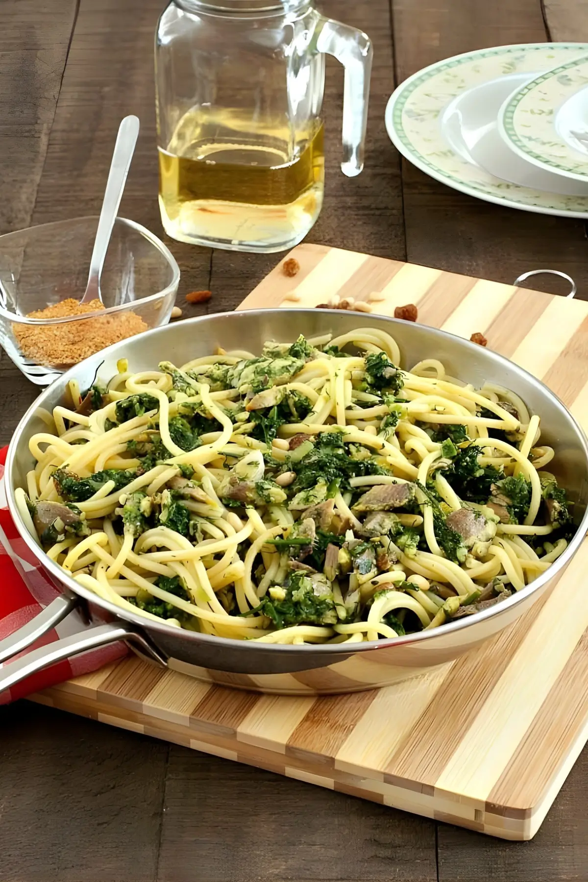 Pan of pasta with sardines, fennel, raisins, and pine nuts, served with toasted breadcrumbs on the side.
