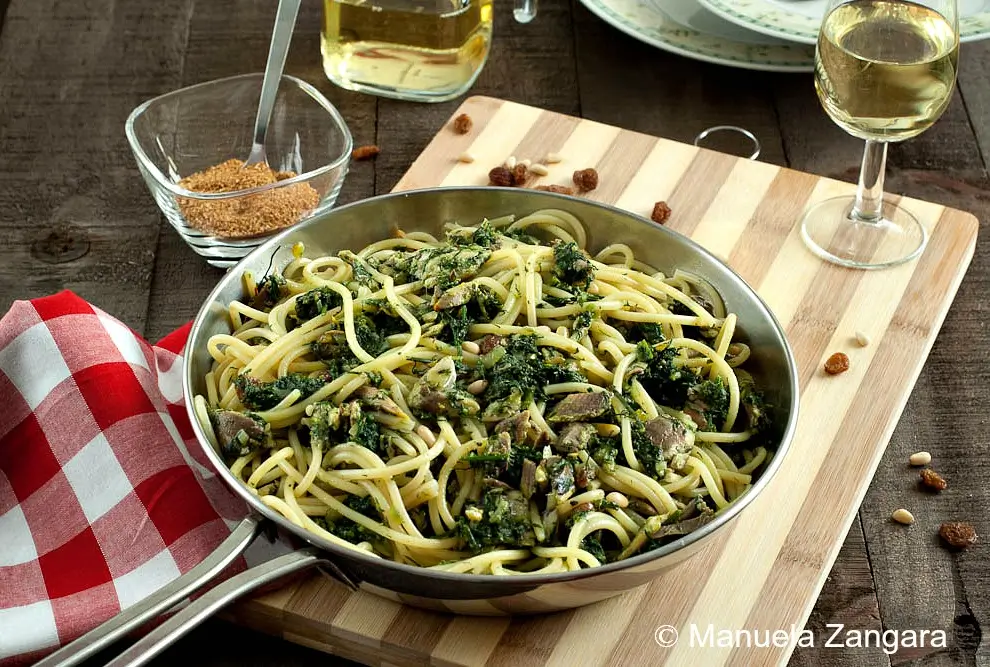 Finished bucatini with sardines and fennel in a pan, served with wine and toasted breadcrumbs.