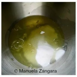 Egg whites and sugar in a metal mixing bowl.