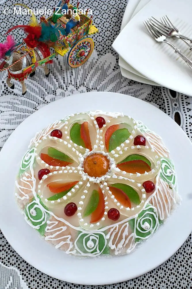 Traditional Sicilian cassata topped with orange, cherry, and green candied fruit decorations.