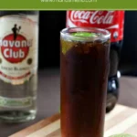 Cuba Libre with fresh lime on a wooden board.