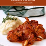 Italian rabbit stew served with mashed potatoes on a white plate.