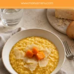 Pumpkin risotto served with pumpkin cubes and Parmigiano Reggiano slivers.