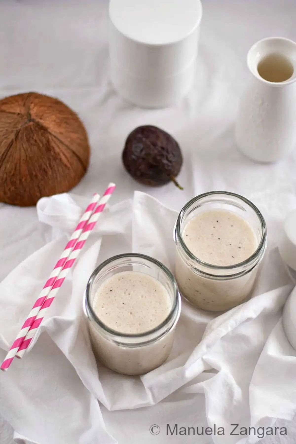 Creamy coconut and passion fruit smoothie served cold in glass jars.