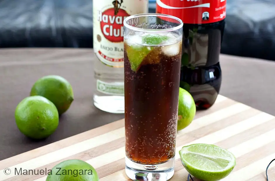 Cuba Libre served in a tall glass with lime and ice.