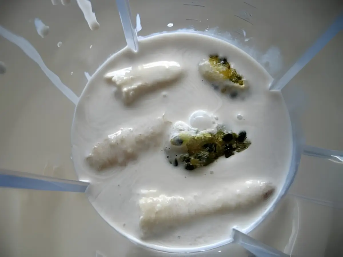 Banana, coconut cream, honey, and passion fruit pulp added to a blender before mixing.