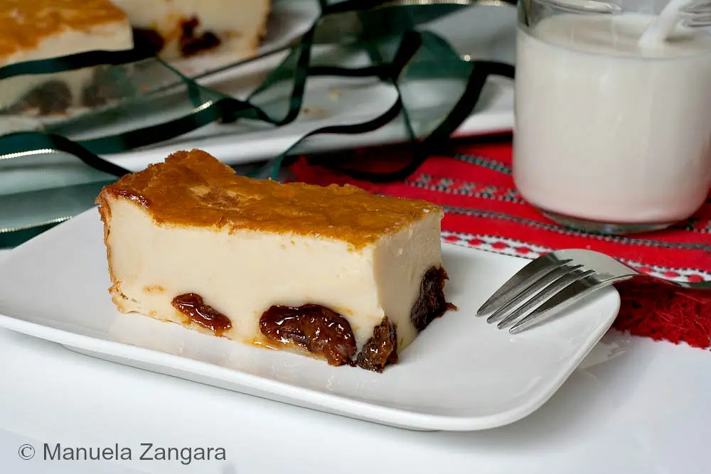 Slice of Far Breton served on a small plate beside a glass of milk.