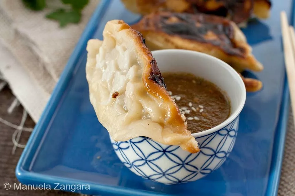 Close-up of a Kothey Momo dipped in spicy tomato chutney.