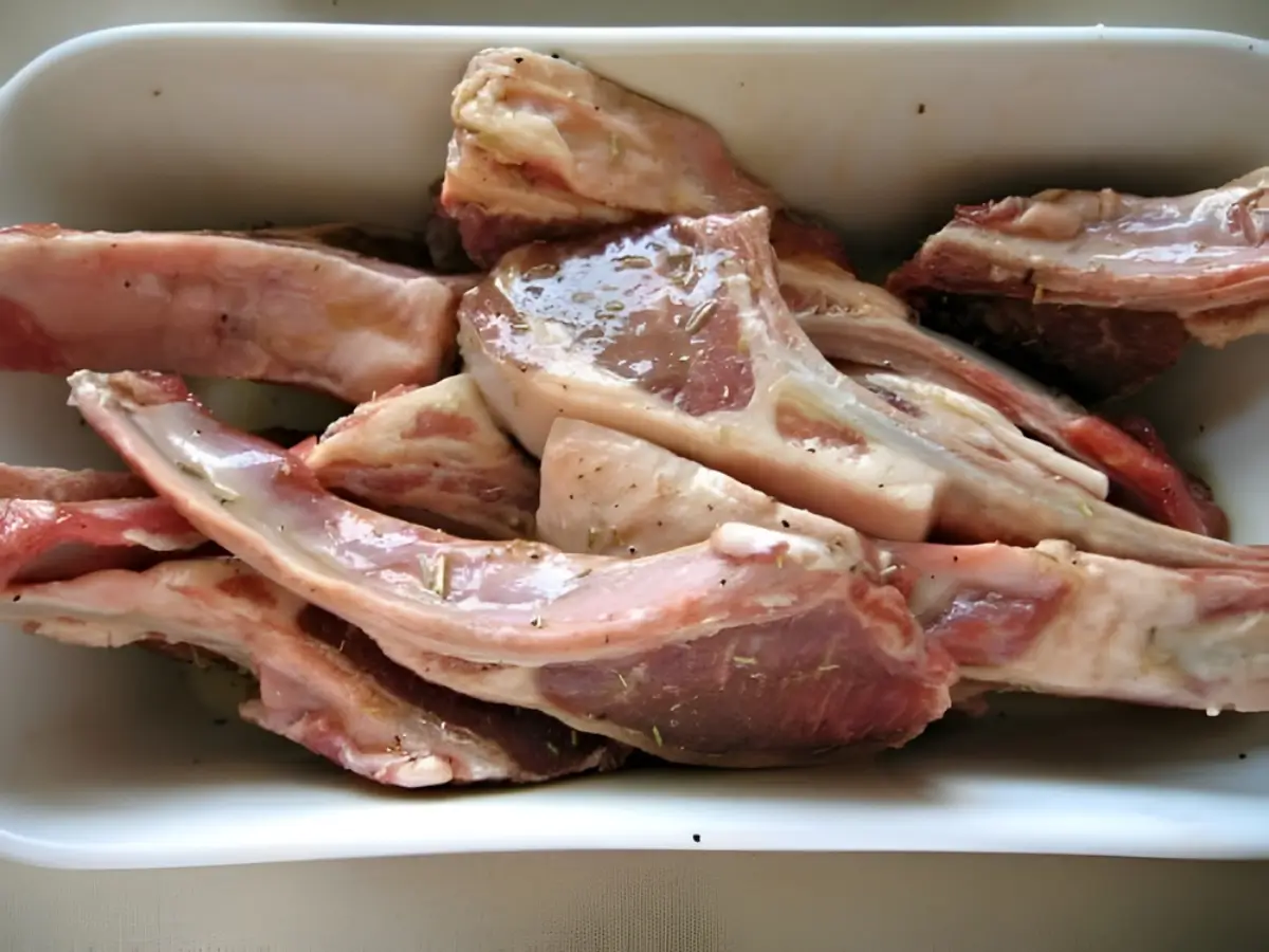 Raw lamb cutlets coated in rosemary, garlic and oil before marinating.