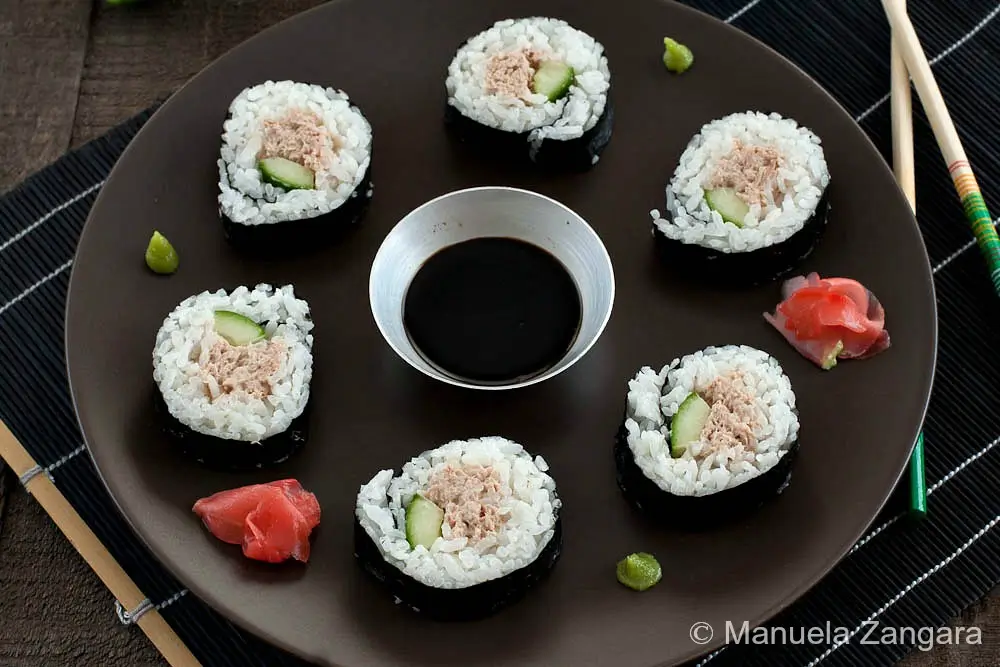 Spicy Tuna Salad Sushi Rolls Sushi rolls arranged on a dark plate with soy sauce, ginger, and wasabi.
