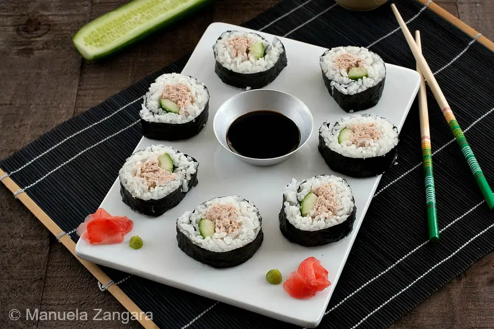 Spicy Tuna Salad Sushi Rolls Sushi rolls displayed on a white serving board with chopsticks, ginger, and wasabi.