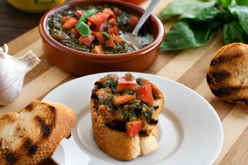 Grilled bruschetta topped with fresh tomato condiment beside a bowl of Matarocco.