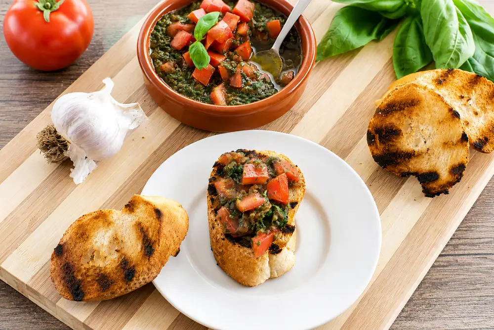 Rustic tomato and basil condiment served with toasted bruschetta on a wooden board.