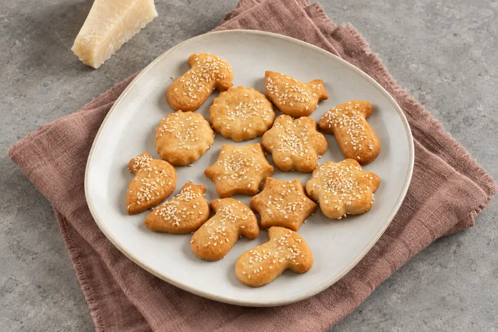 Baked cheese cookies topped with sesame seeds and served on a ceramic plate.