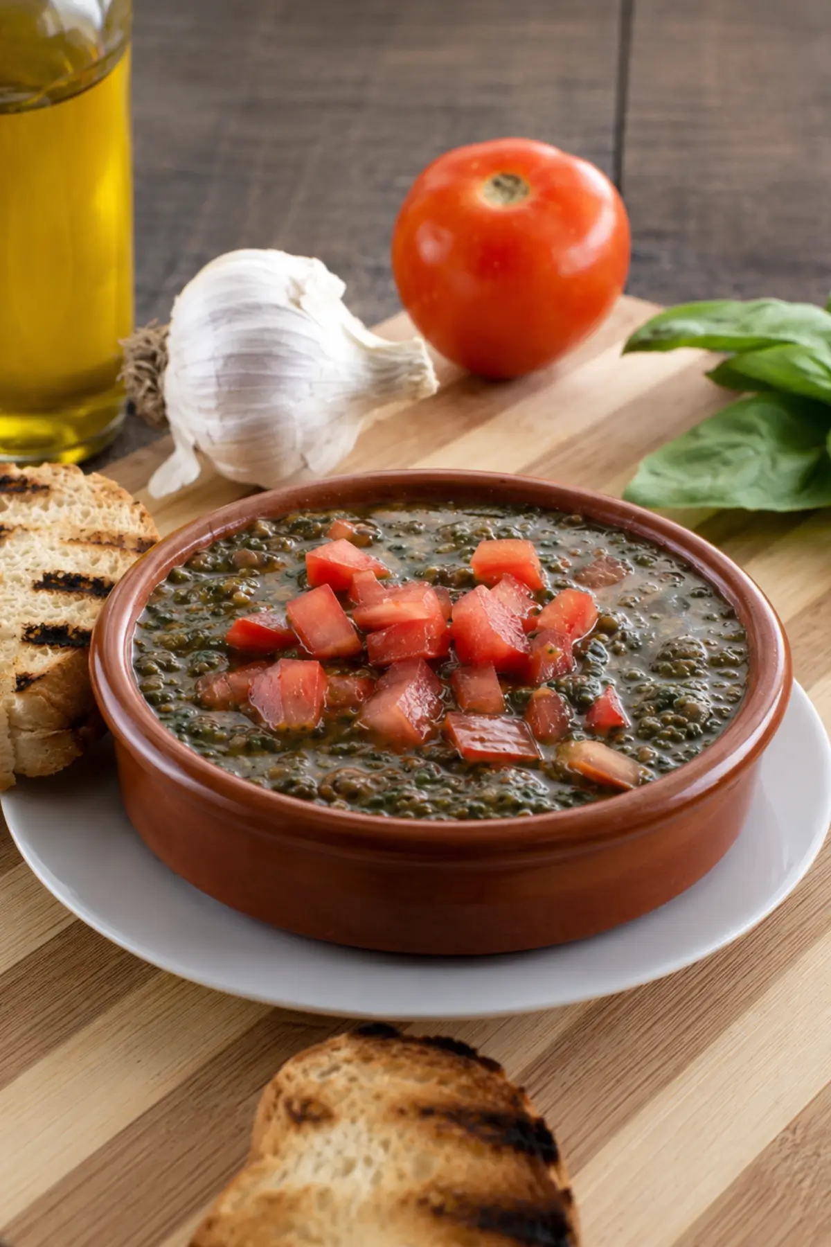Bowl of fresh tomato and basil condiment surrounded by grilled bread and garlic.