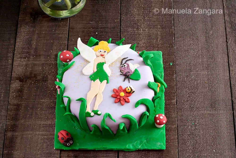 Tinkerbell fondant cake on a wooden table with mushrooms, flowers and Blaze.