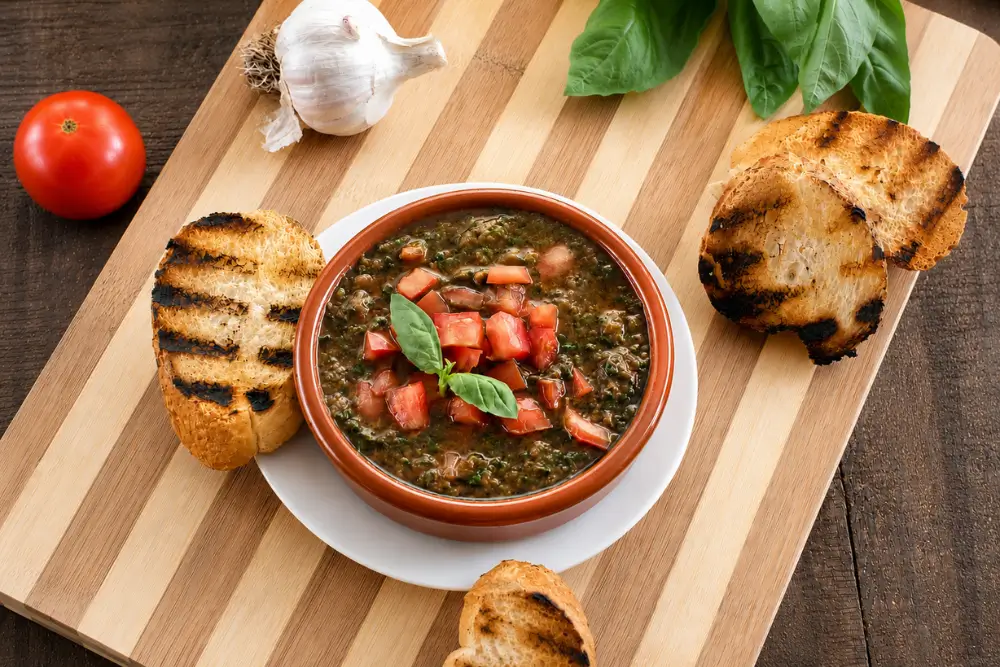 Rustic bowl of fresh tomato condiment served with grilled crostini and basil leaves.
