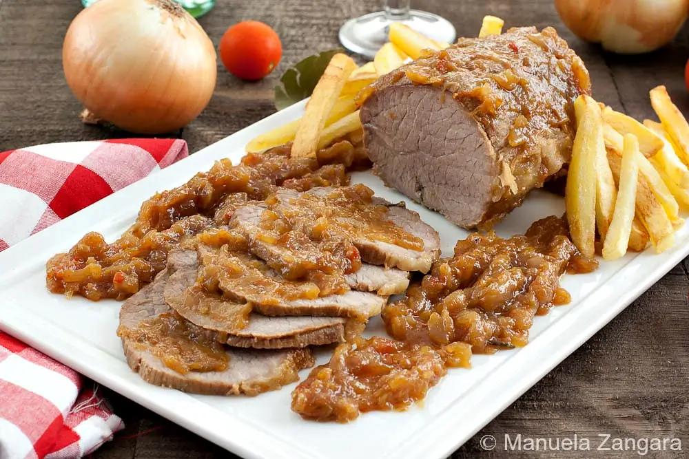 Sliced beef roast topped with onion glaze and served with fries.