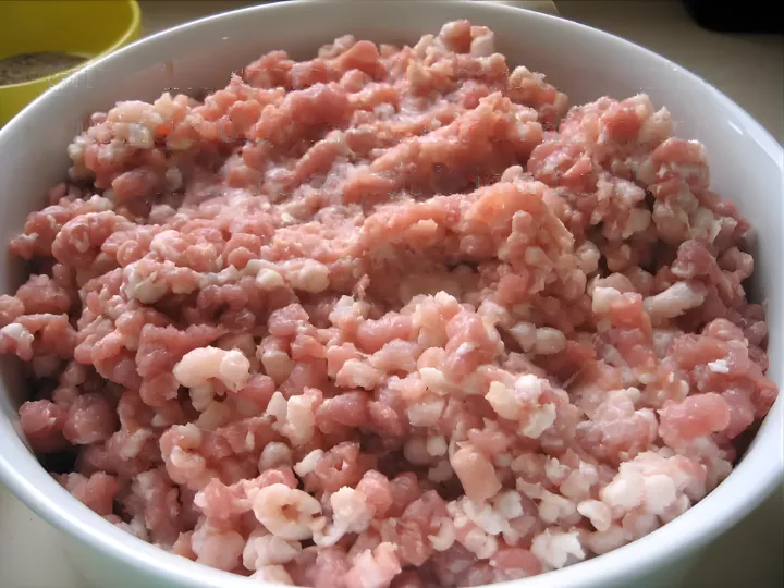 Ground pork and fat mixture in a white bowl prepared for making Sicilian fennel sausage.