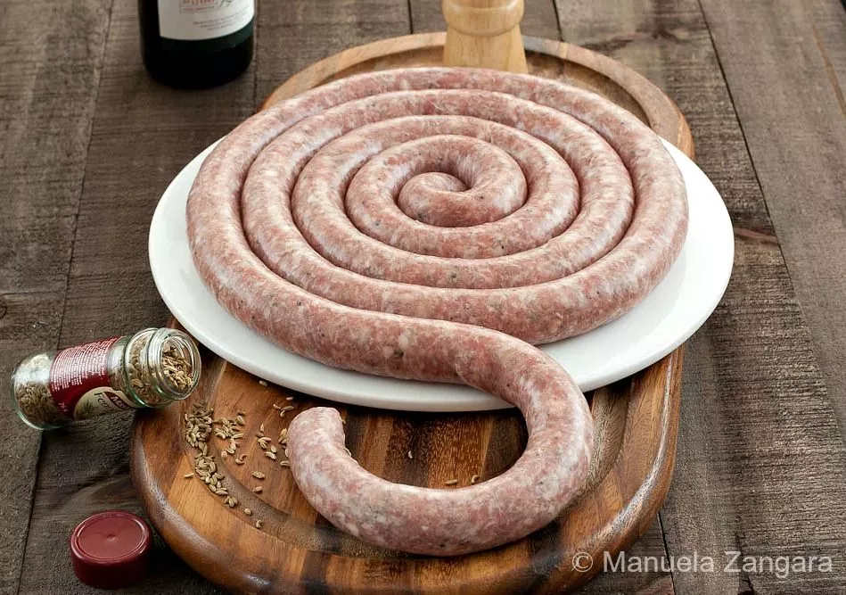 Homemade Sicilian Pork Sausage with Fennel coiled on a wooden board.