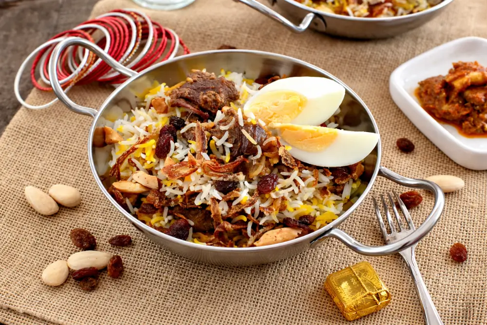 Indian biryani topped with nuts, sultanas, and fried onions on a rustic table.