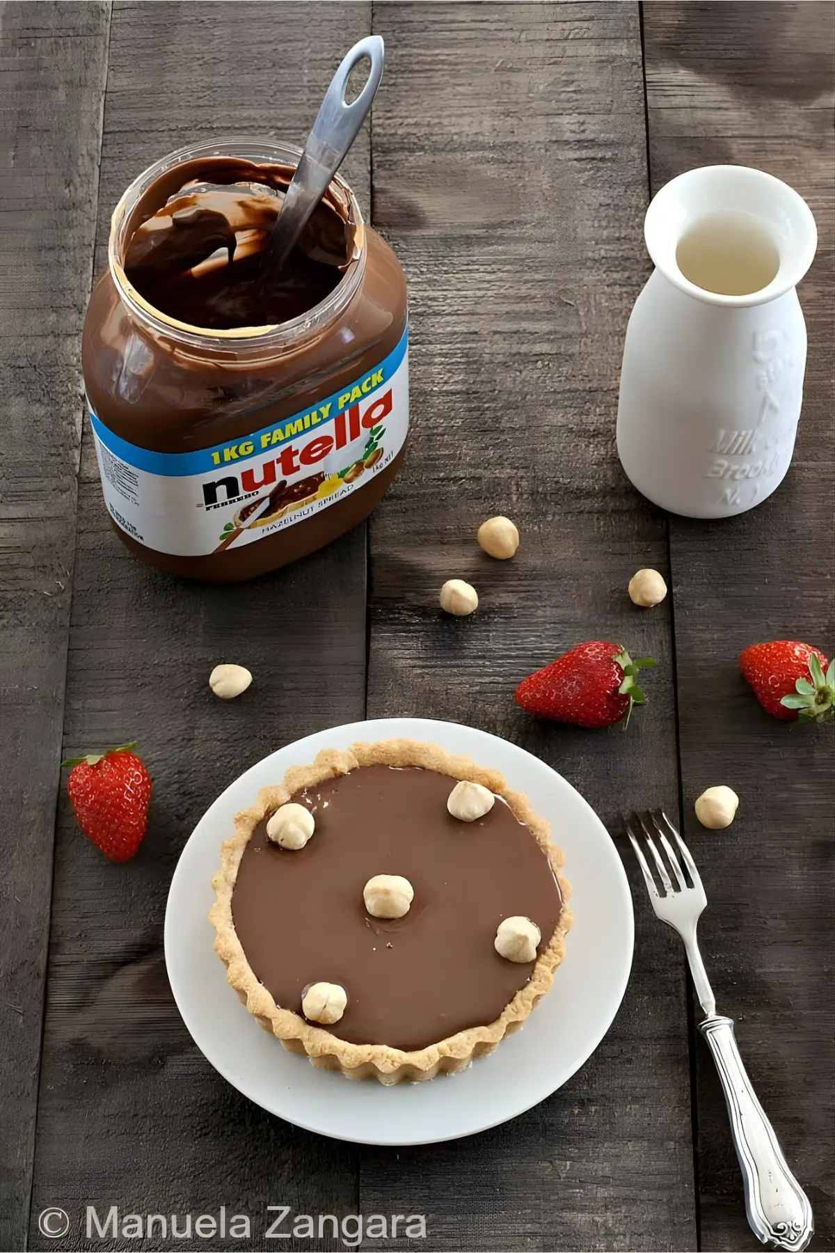Nutella tart on a plate with a jar of Nutella and fresh strawberries.