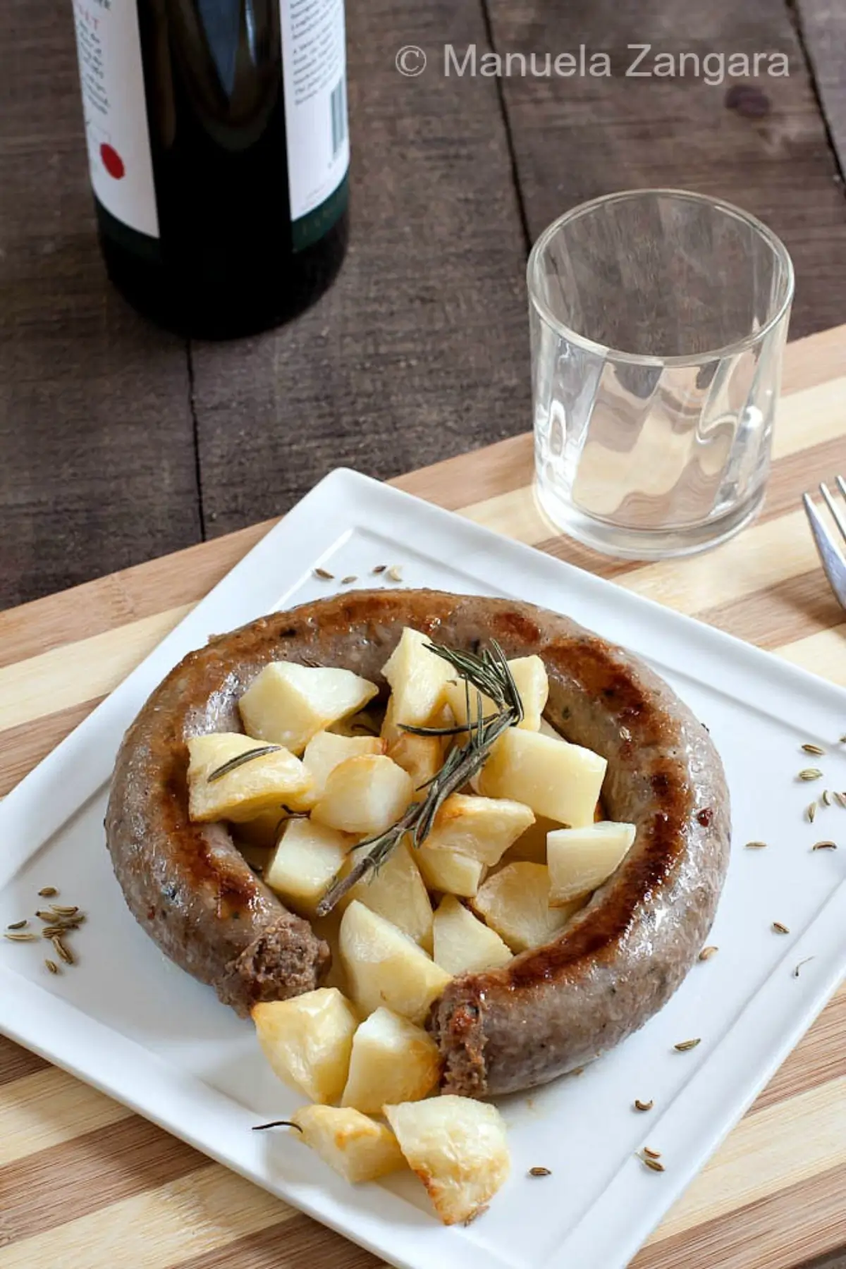 Pan-fried sausage served with roasted potatoes and rosemary.