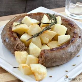 Close-up of pan-fried sausage with golden potatoes and fennel seeds.