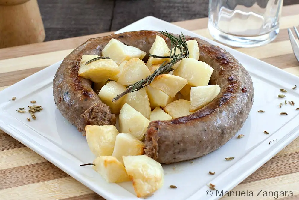 Close-up of pan-fried sausage with golden potatoes and fennel seeds.