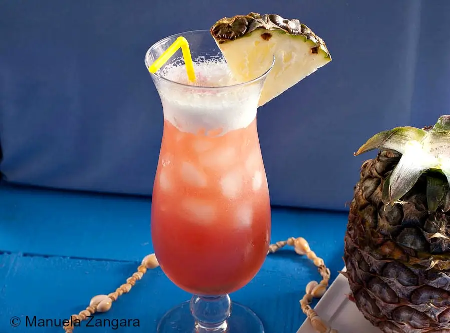 A Mai Tai served over ice with a frothy top and pineapple garnish.