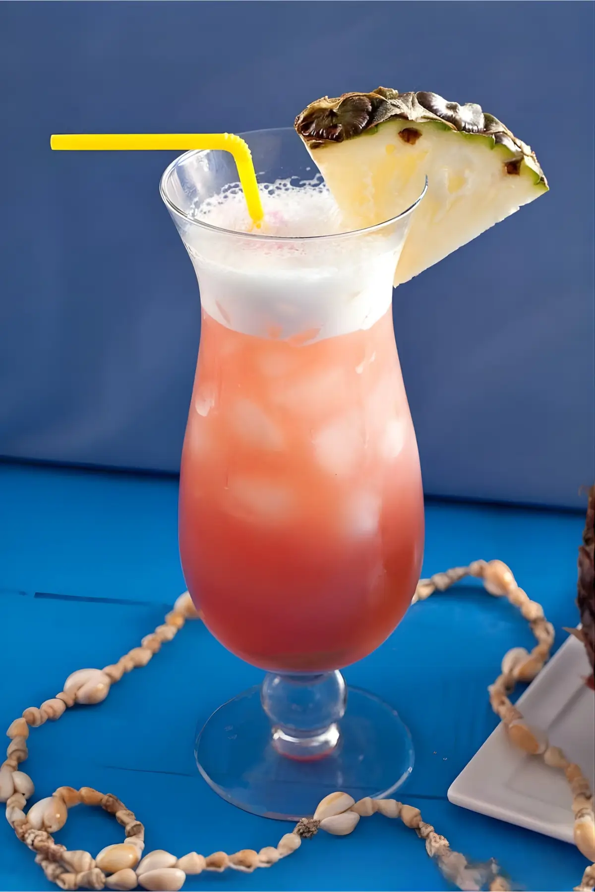 Finished Mai Tai cocktail served in a tall glass with ice, creamy top, and a pineapple slice.