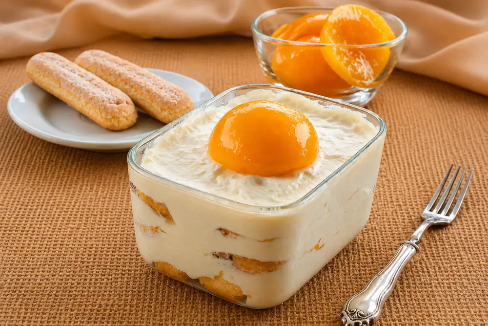 No-Bake Peach Tiramisu with Ladyfingers in a glass dish.
