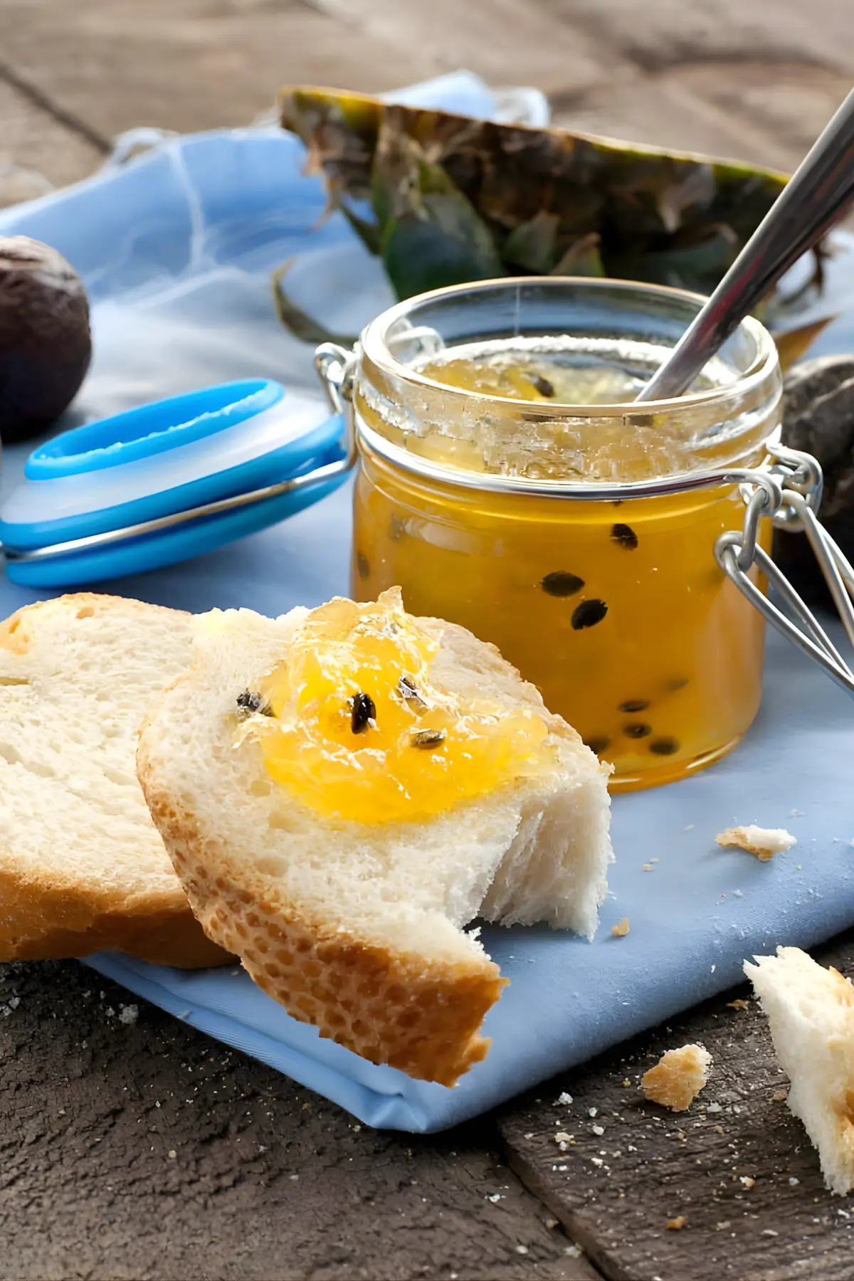 Slice of bread topped with pineapple and passion fruit jam next to an open jar.