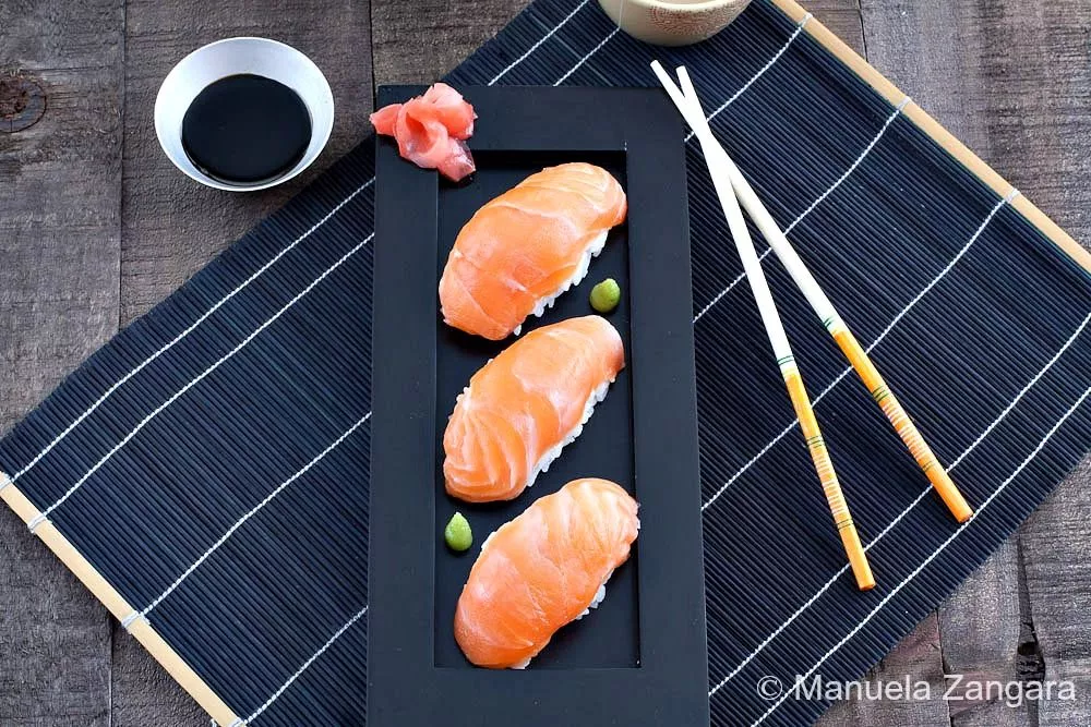 Top view of Salmon Nigiri sushi with chopsticks, soy sauce, and pickled ginger.