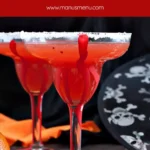 Two Blood Orange Margaritas with salted rim and oranges on table.
