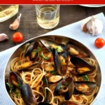 Spaghetti with Mussels in tomato and white wine sauce, garnished with parsley and cherry tomatoes.