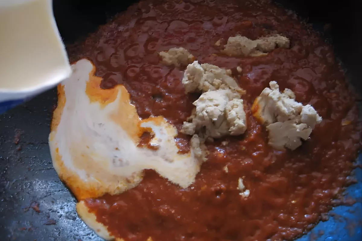 Cream being added to the curry sauce for lamb koftas.