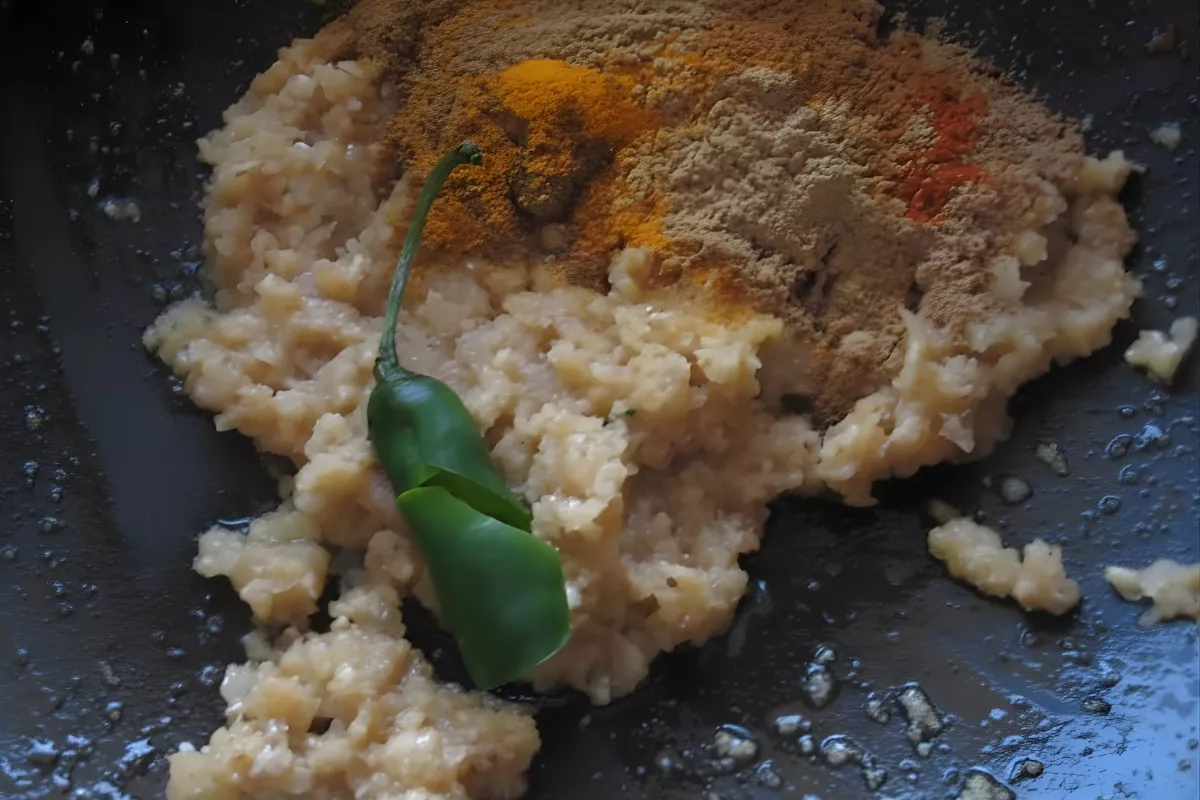 Spices like turmeric, cumin, and coriander added to curry sauce.