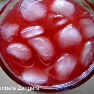 Glass of blood orange margarita filled with ice cubes.