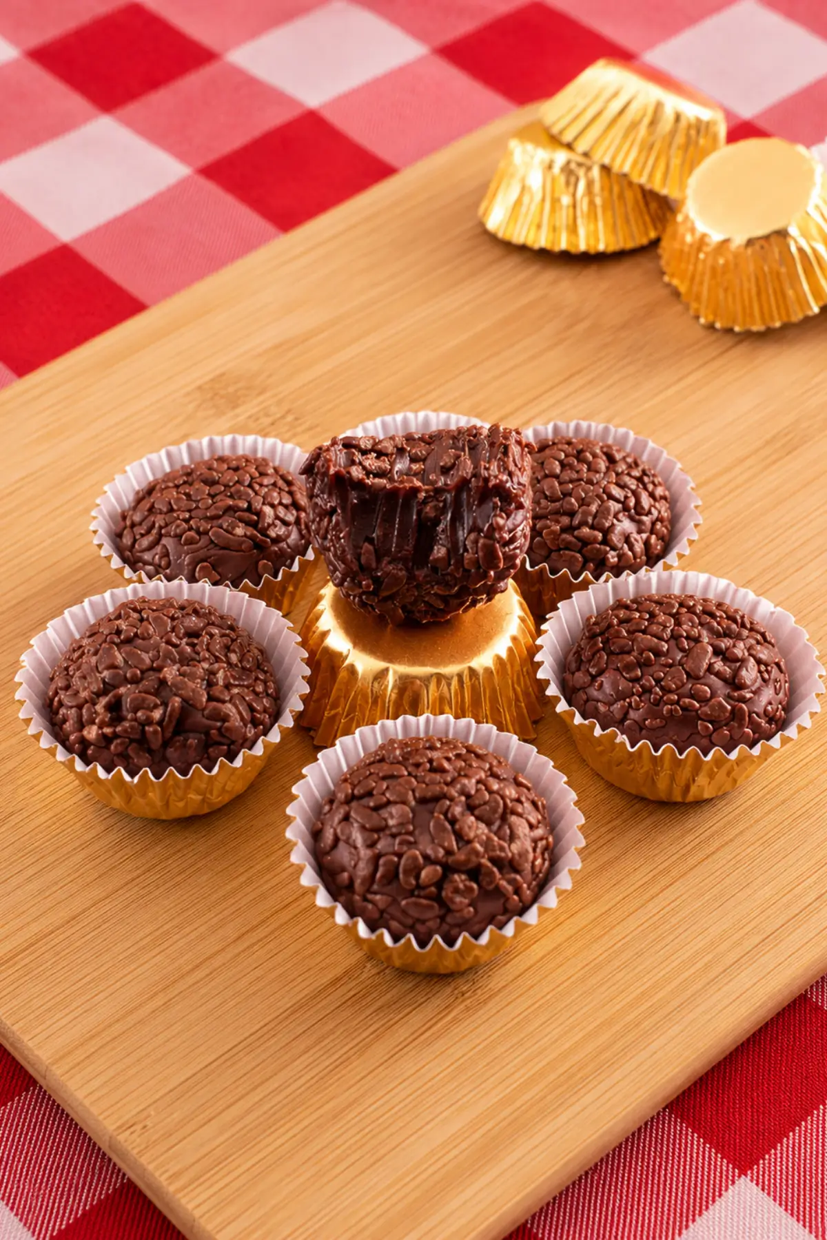 Cut-open chocolate truffle showing the soft fudgy centre, surrounded by coated brigadeiros.