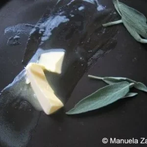 Butter melting with fresh sage leaves in a pan for the sauce.