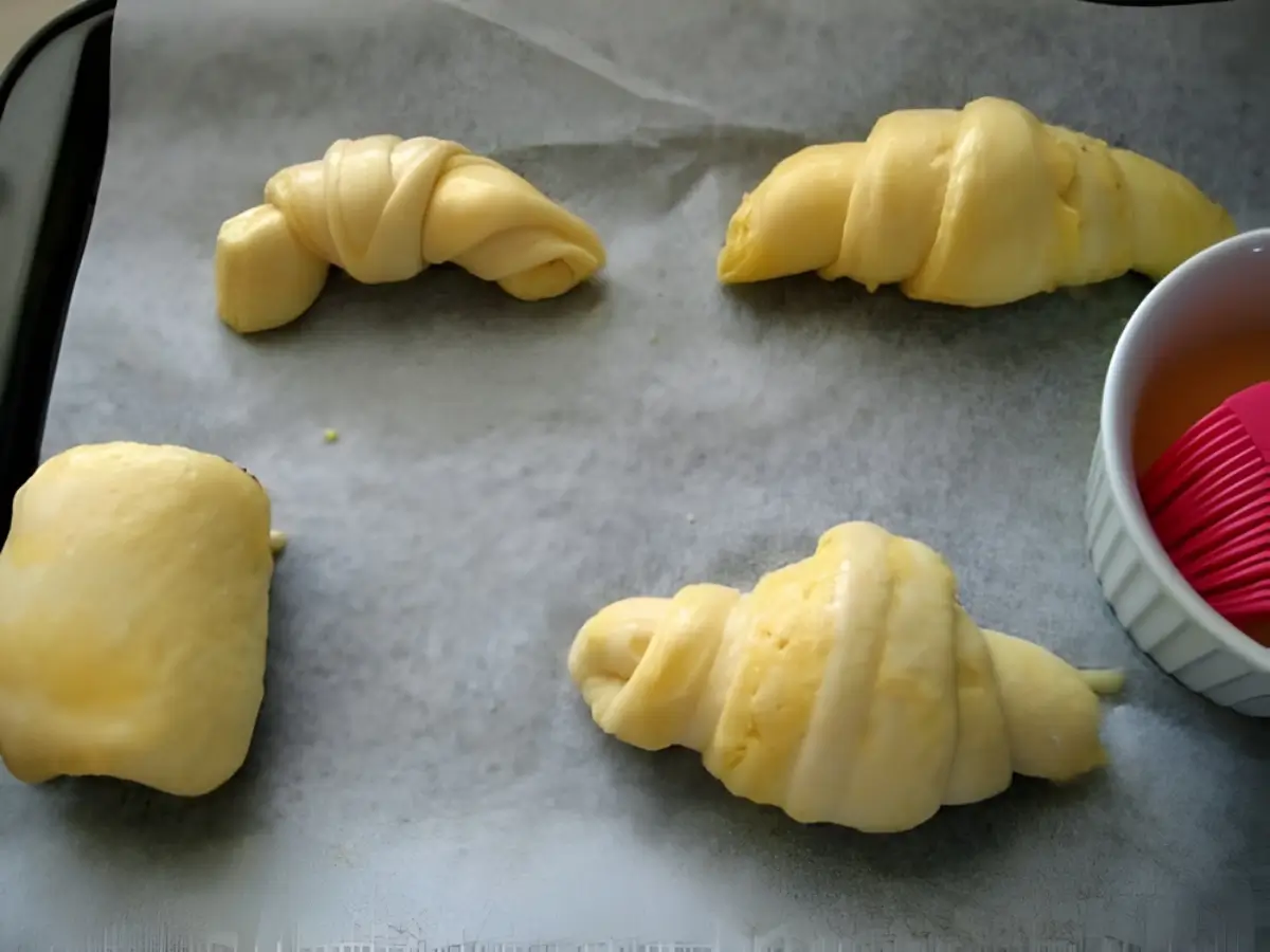 Shaped croissants resting on a parchment-lined tray before baking.