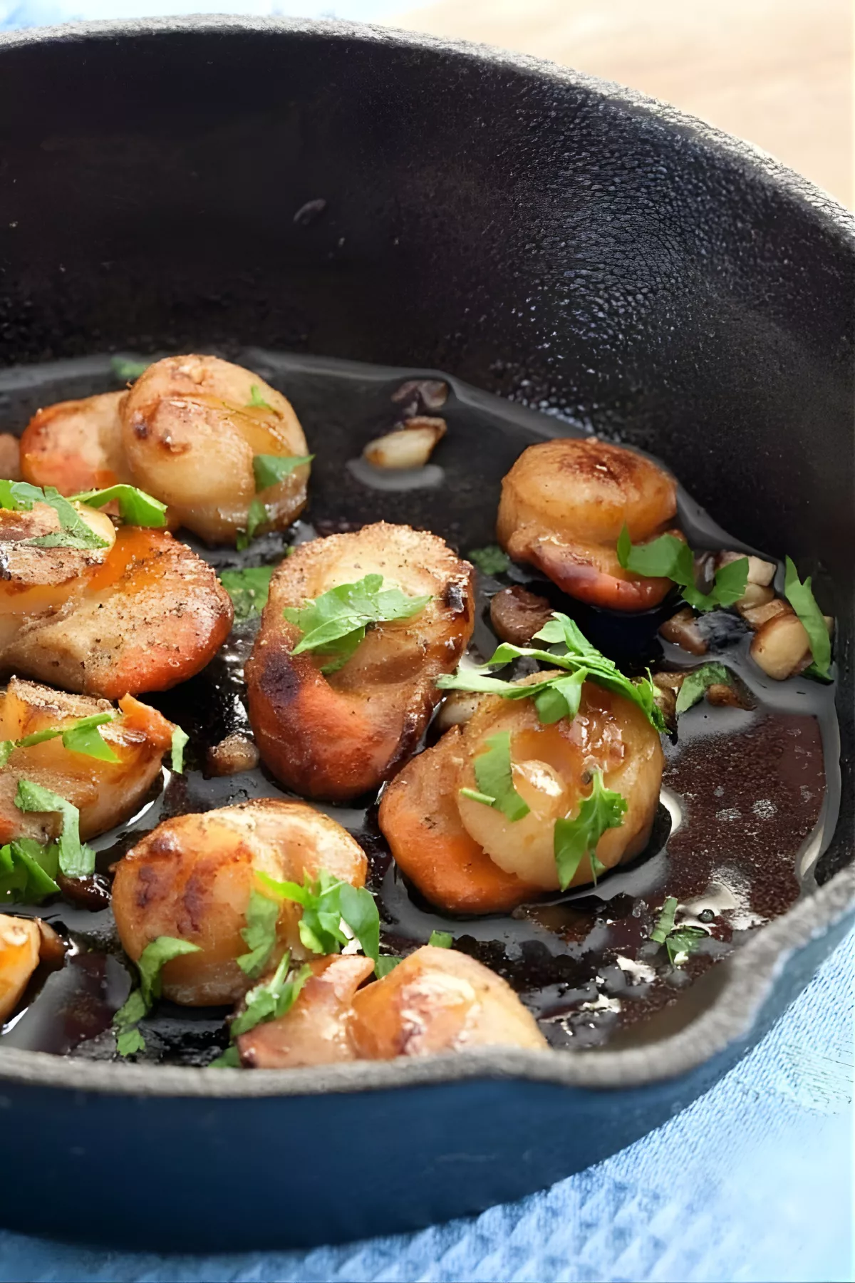 Garlic Scallops seared in a cast iron pan with butter and parsley.