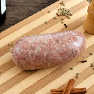 Homemade Cotechino resting on a wooden board with whole spices.