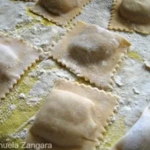 Freshly made tortelli resting on a floured surface before cooking.