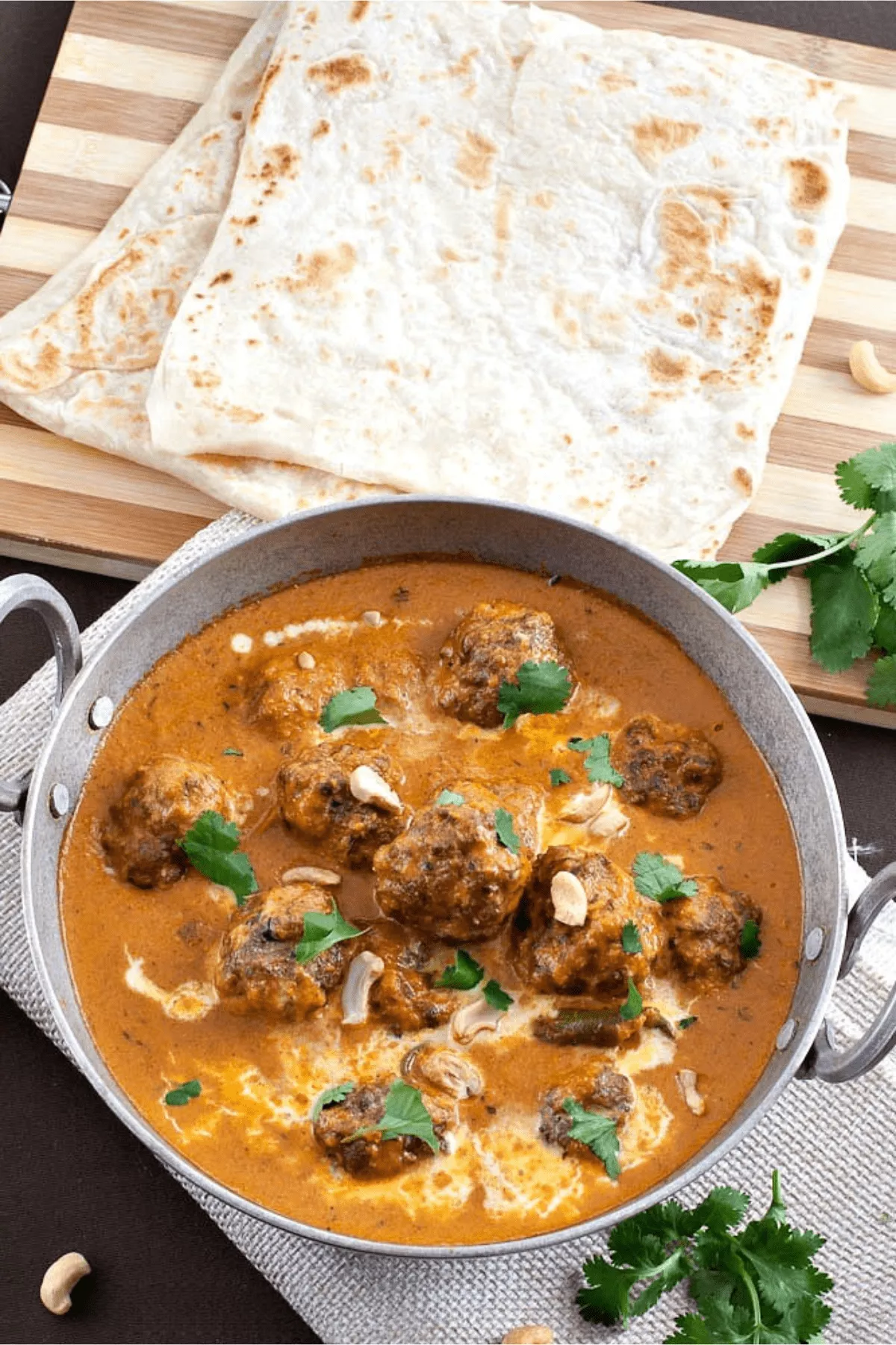 Finished lamb kofta curry served with naan, garnished with cilantro.